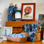 Products with images of peacocks displayed on a shelf in the gift shop